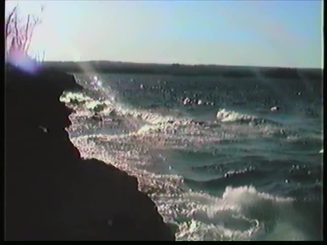 Choppy waves hitting a rocky shoreline under sunlight