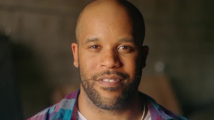 Man stares straight ahead and smiles