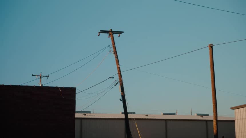Crooked utility pole near buildings