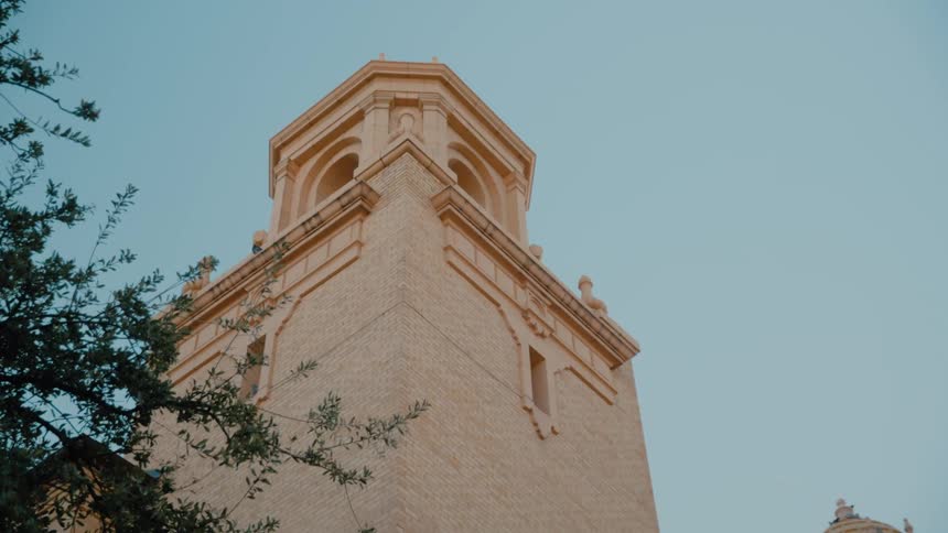 Bell tower stands near a tree on a summer day