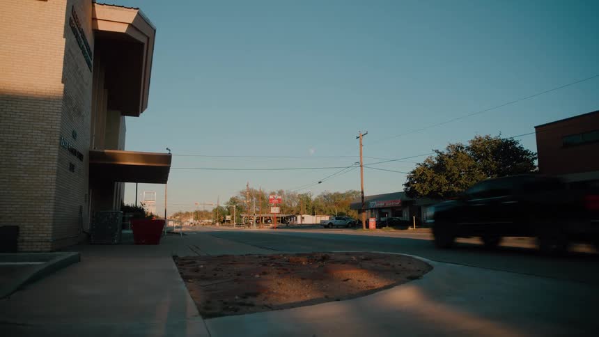 Urban street with pickup truck in motion commercial buildings and utility poles along the road