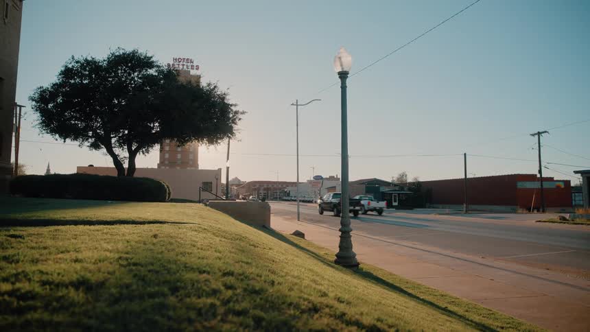 Light traffic moving by buildings into a small town city