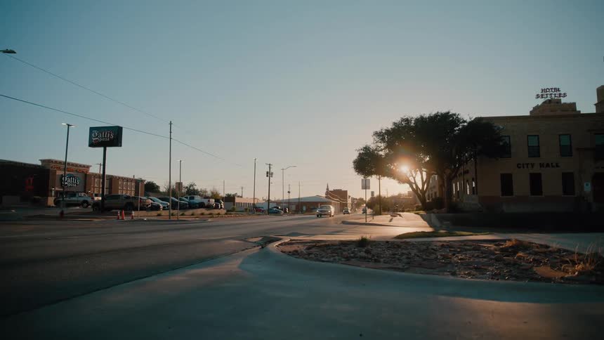 Light traffic moving by buildings into a small town city