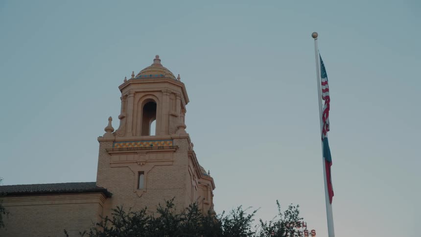 Church tower beside a flagpole with flags raised