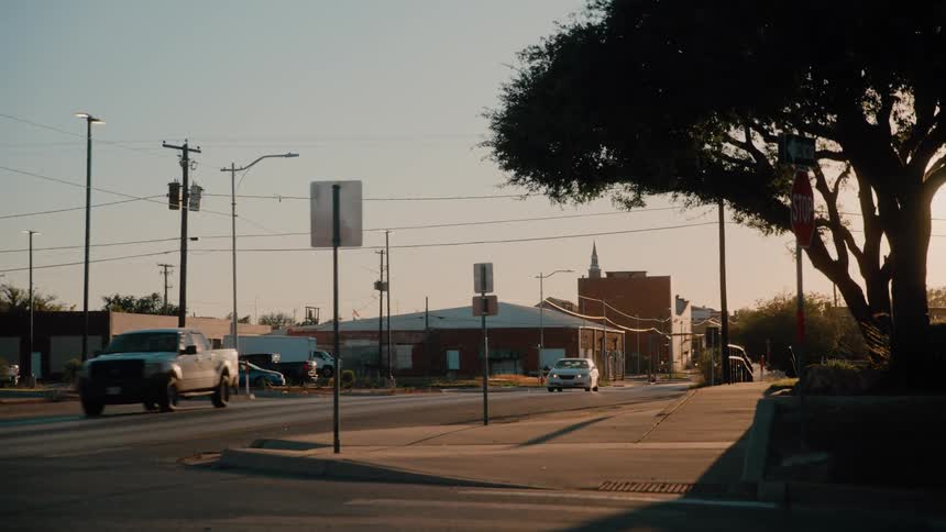 Urban street with vehicles driving and commercial buildings at dusk