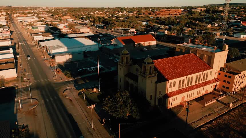 Streets of a city around a historic building with slow traffic on the road and a hill on the background outdoors during dusk or dawn