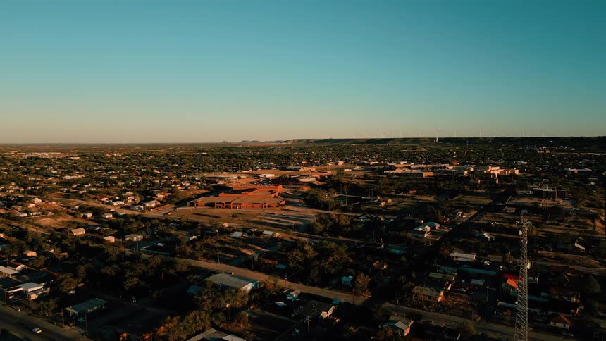 Aerial view of urban area with houses commercial buildings roads and communication towers under clear sky