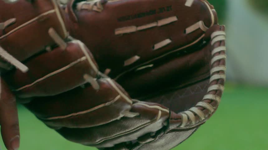 Person catches baseball in baseball glove