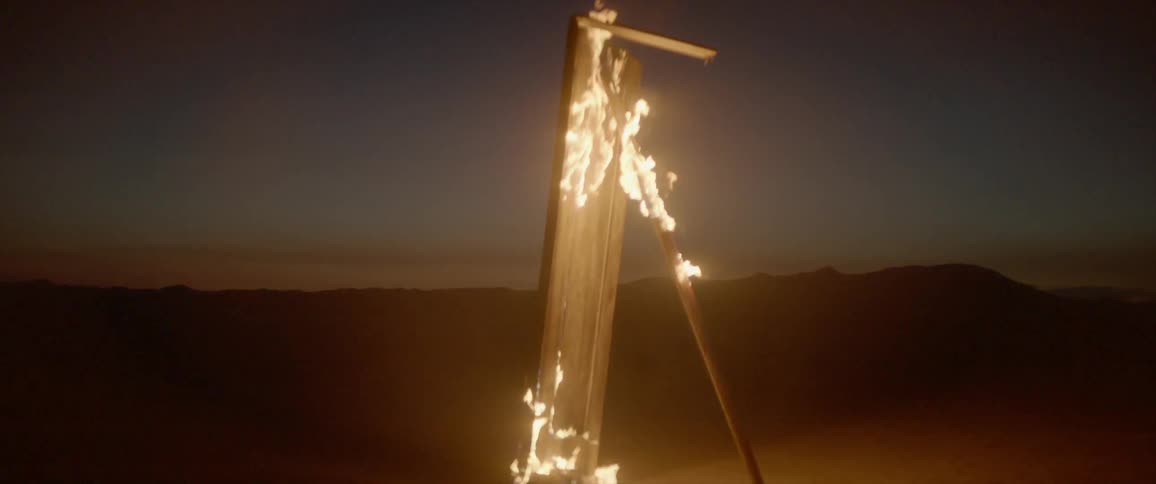 A propped up piece of wood burns at dusk