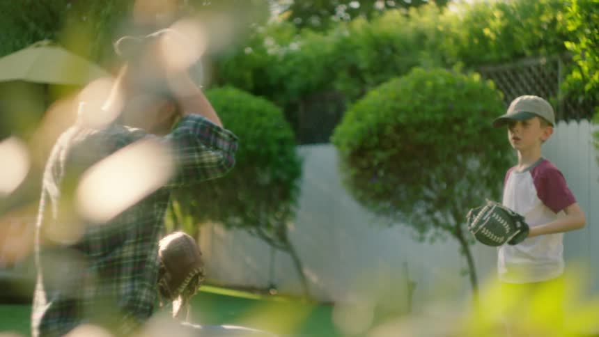 A father and son play catch in the yard
