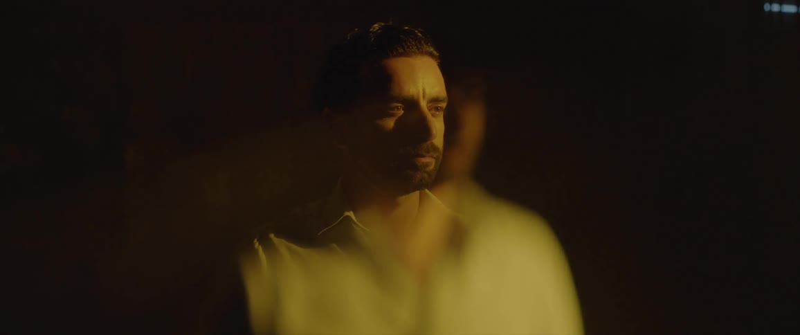 Bearded man standing and coming into and out of view depending on the lighting