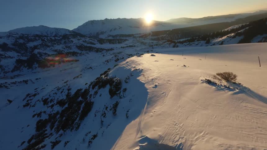 An aerial view of a snowy mountain ridge during sunset