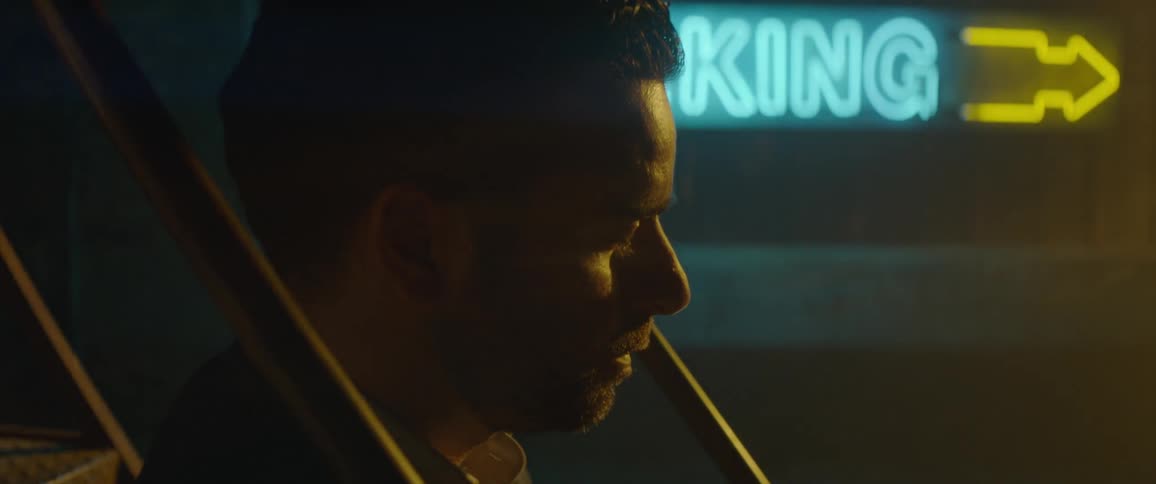 A sign glows behind a man's head