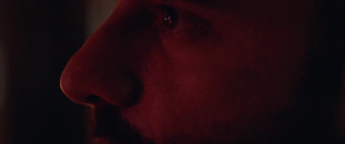A red light glows on a man's face