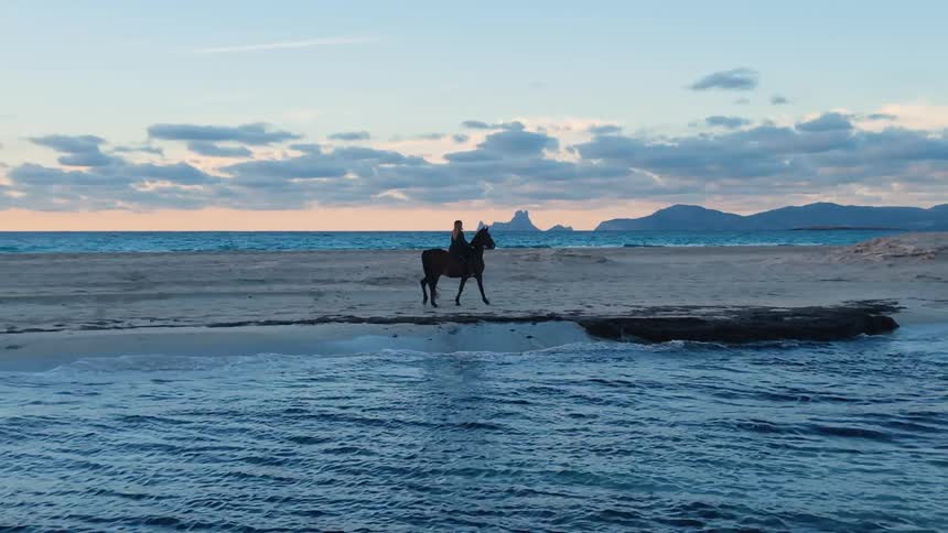 A woman riding a horse on a beach