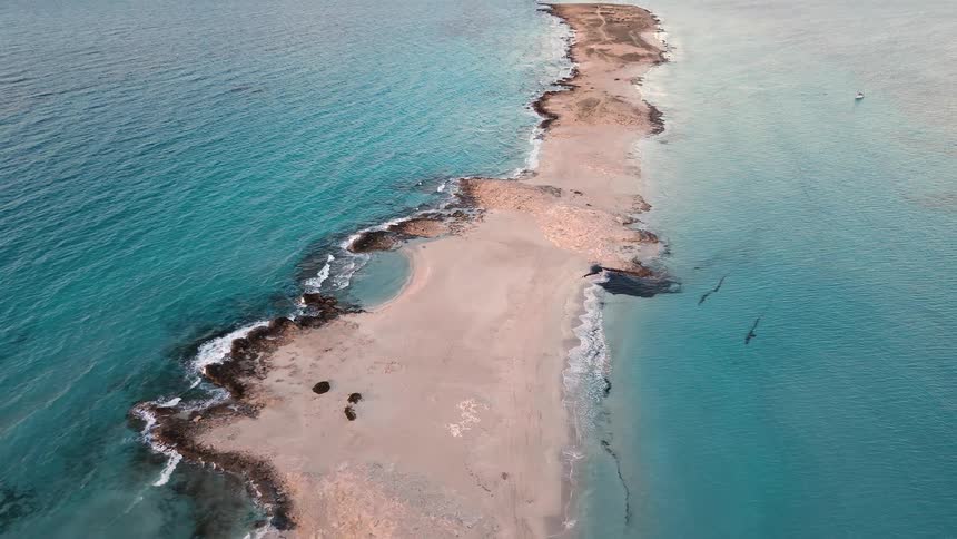 An aerial view of a sand bar with waves