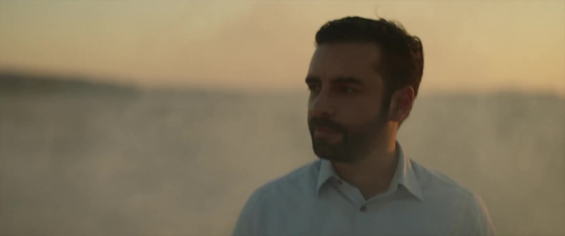 Bearded man standing outdoors with smoke passing by him