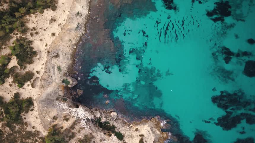 Aerial view of cove with turquoise water rocky cliffs and vegetation along the edges