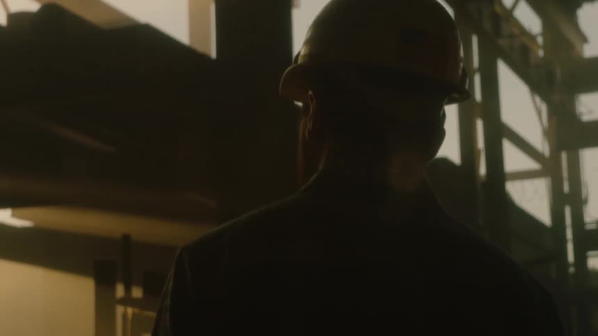 A man in a hard hat walks in a building