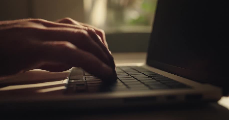 close up of fingers typing on a laptop in a sunny afternoon setting
