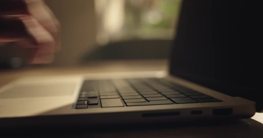 Mans fingers pressing keys on the keyboard of a laptop computer