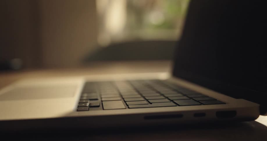 close up of hands opening a laptop and typing on it