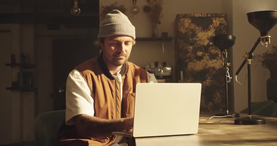 Creative designer sitting at a table typing on a laptop computer and he closes the lid