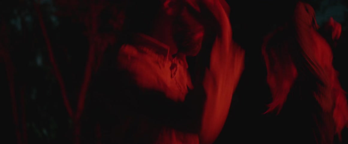 A man and woman dance in red light