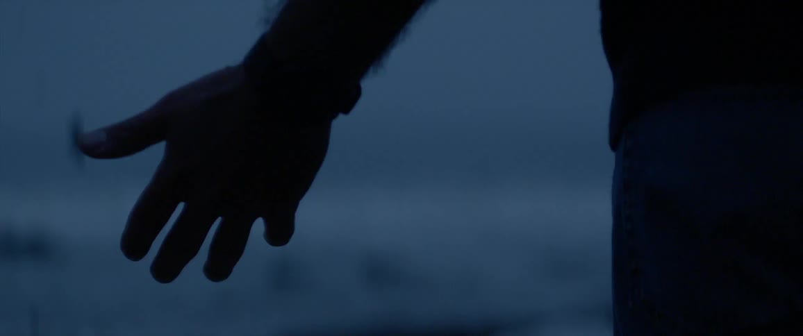 Person holds their hand out in the rain in the evening
