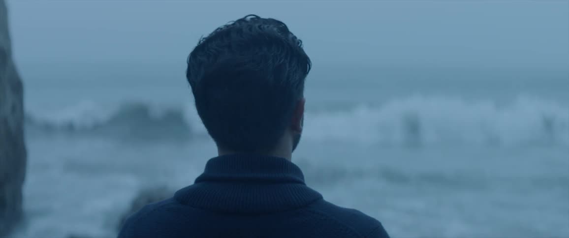 Man looks out at the ocean on a dark day