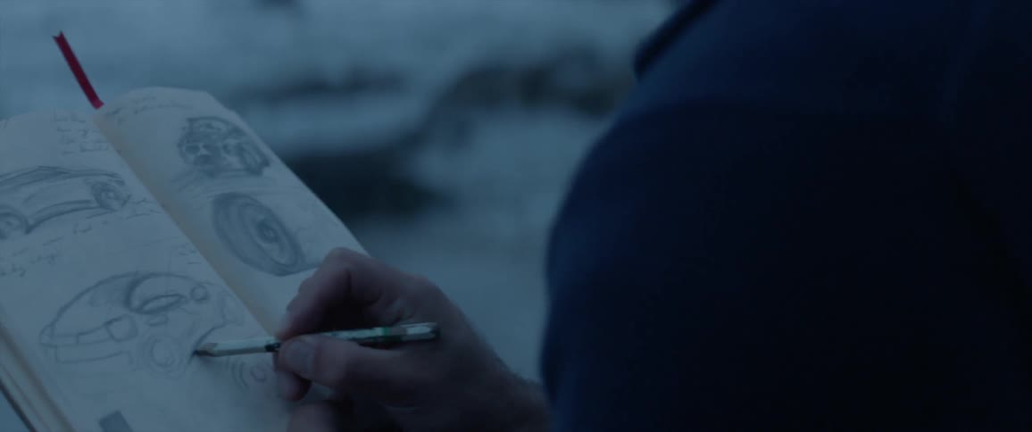 Person sitting outside drawing in a notebook at dusk