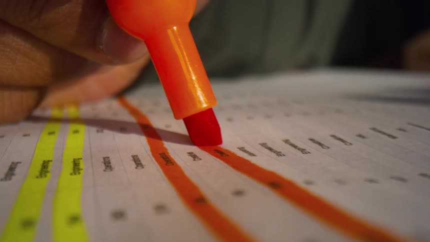 Orange highlighter marking line of text on printed document on table