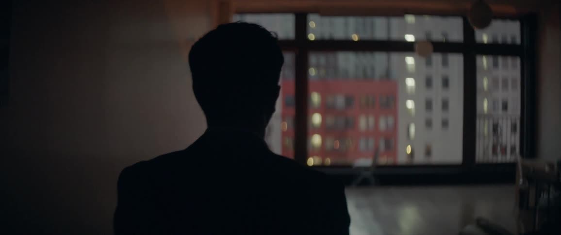 A man walks down a hallway towards a large window