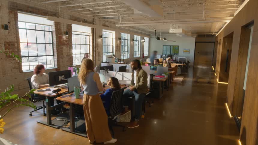 Spacious office with aligned desks computers and team working near large windows