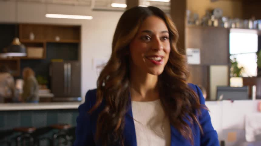 A woman walking into an office full of workers