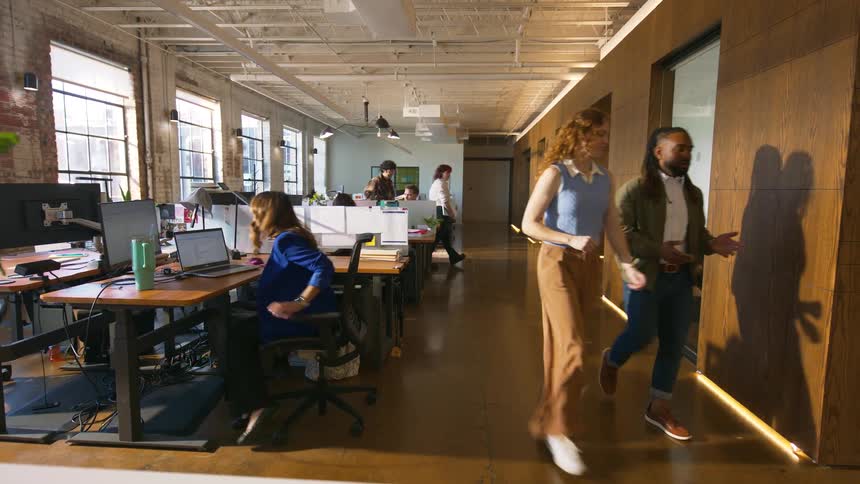 People work at desks and walk through a modern open plan office