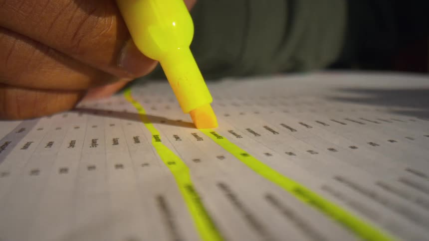 Yellow highlighter marking lines of text on printed document on table