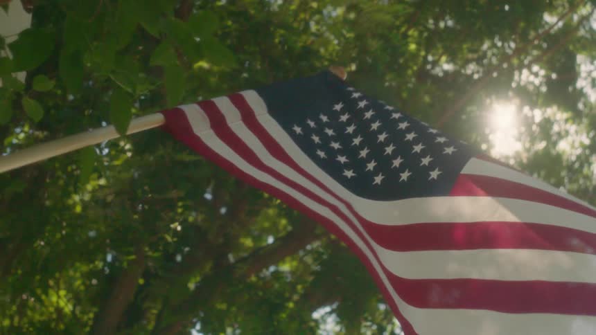 A woman hangs a flag on a pole on a sunny day