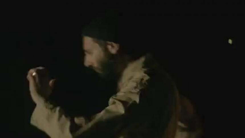 A man dances in the dark as lights flash
