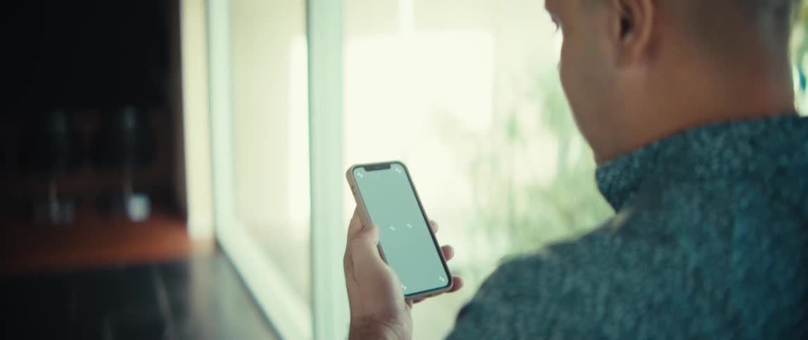 Man holds a smartphone with a bright screen while standing indoors