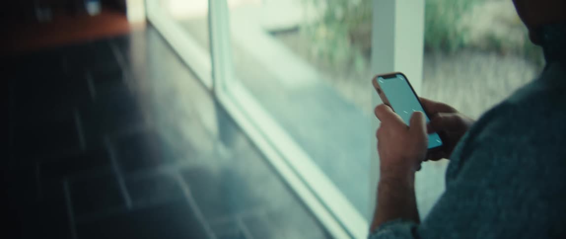 Man holds his phone with both hands moving his thumbs across the screen