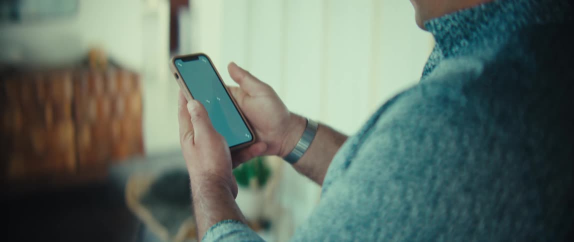 Man walks through a room looking at his phone in his hand