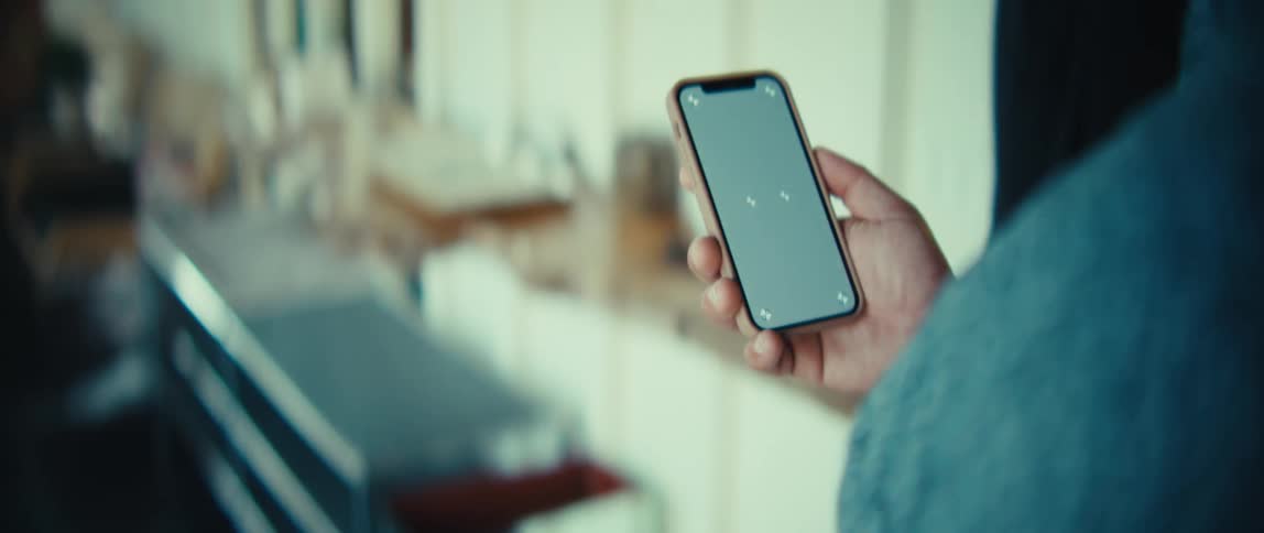 The man walks in his home while holding a cell phone up