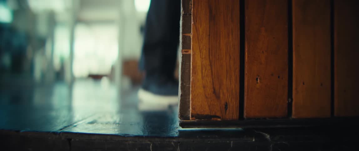 The man opens the wood door and leaves