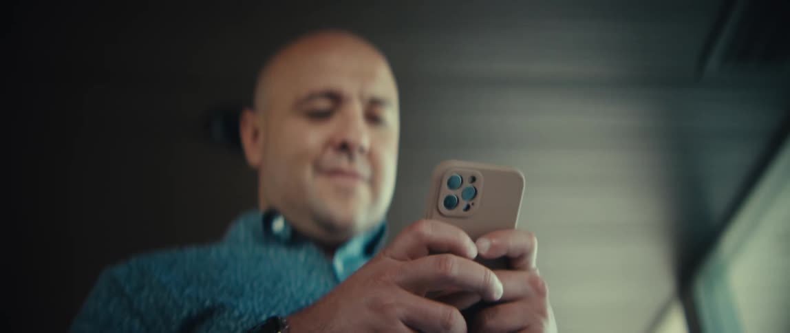Man holds his phone with both hands texting as he walks