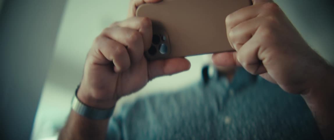 Man holding smartphone horizontally with both hands indoors