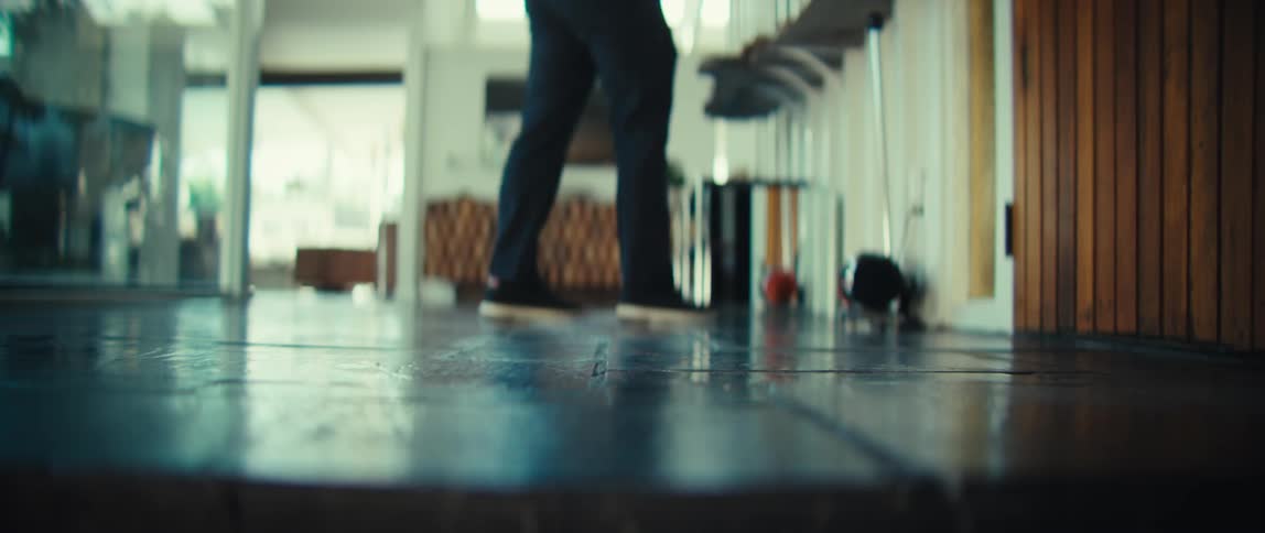 A man walks across a modern tiled floor in a spacious bright house