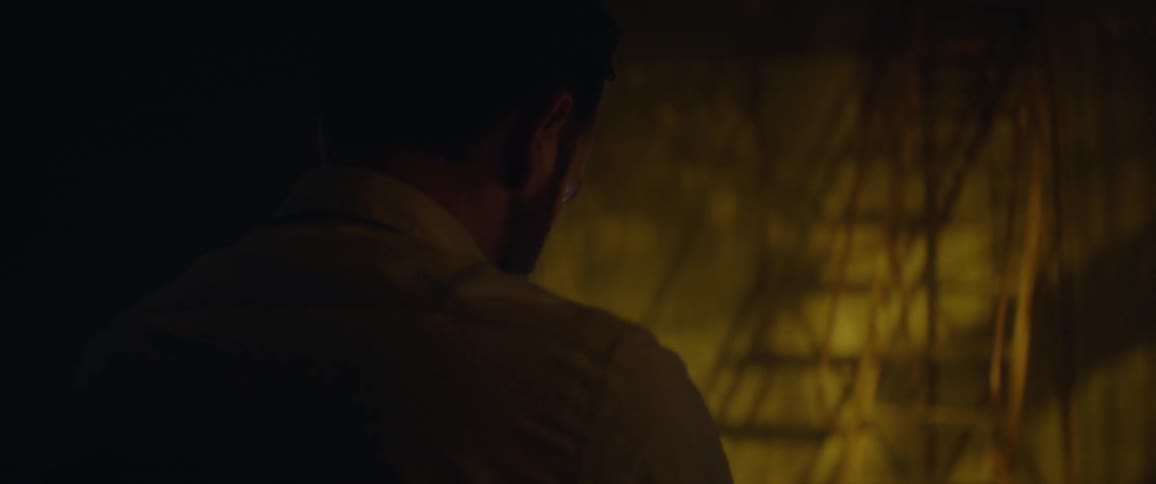 A man looks down at a table with a lamp on