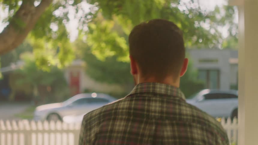 Man walks outside out a house into a yard
