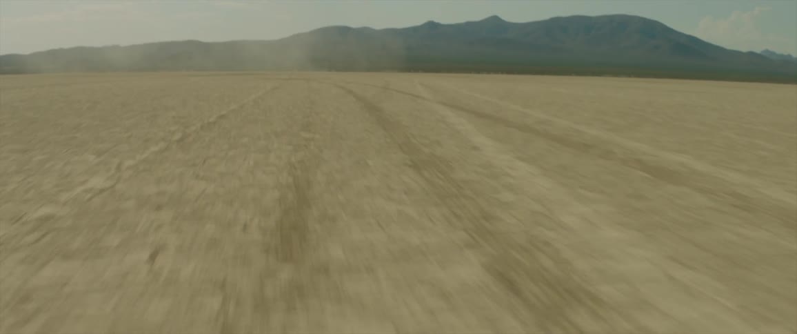 A large dirt field is shown in the wilderness